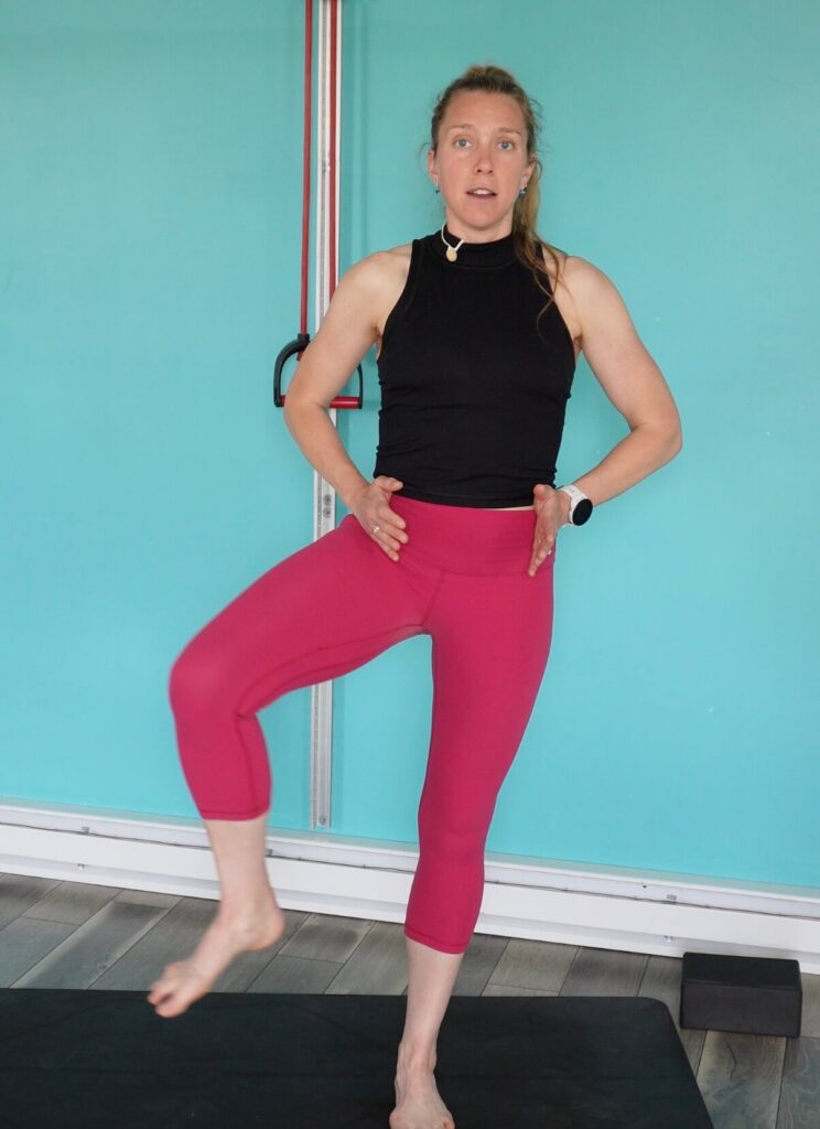 Dr. Chloe balancing on her left foot with her right knee bent at 90 degrees and her hip opening out to the side while keeping her pelvis facing straight forward as a trail running exercise